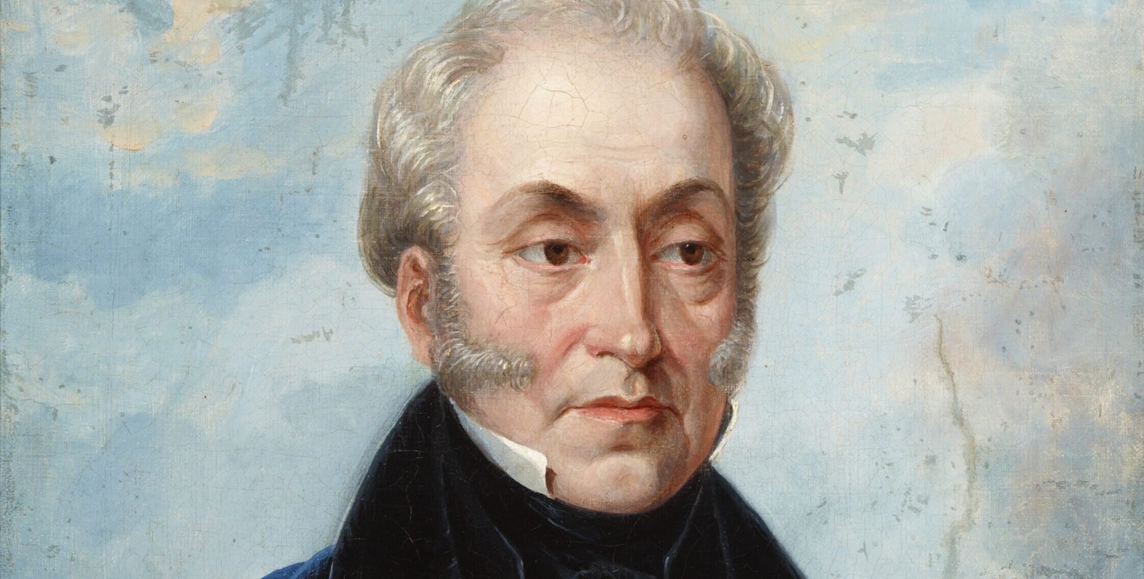 Malarski portret półpostać mężczyzny o jasnych, siwiejących włosach i bokobrodach, zwróconego trzy czwarte, ubrany w białą koszulę, czarną muszkę i ciemny płaszcz z granatowym okryciem, na jasnoniebieskim, lekko chmurowym tle.